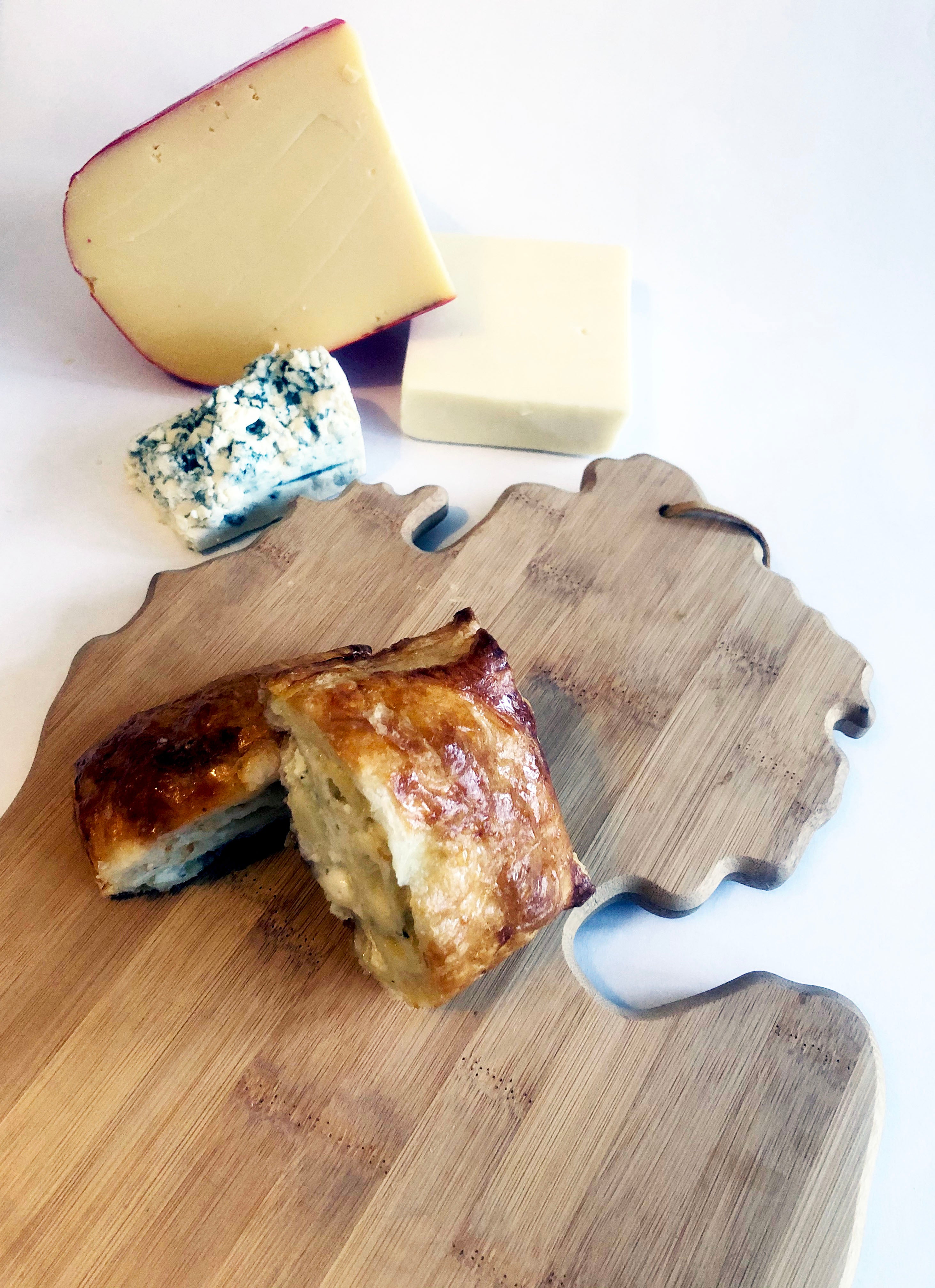 A hand pie on a Michigan-shaped wooden cutting board, with a chunk of blue cheese